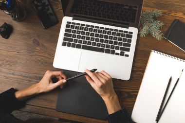 tasarımcı grafik tableti kullanarak ve dizüstü bilgisayar ile işyerinde çalışan kısmi görünümü 