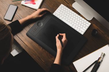 Kısmi görünümü tasarımcısının işyeri masaüstü bilgisayar ve smartphone ile grafik tablet kullanma