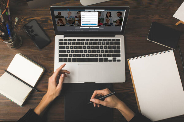 обрезанный снимок дизайнера с помощью графического планшета и ноутбука с ссылкой на сайт на экране
 