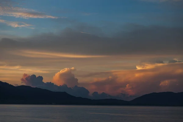 Hermoso cielo nublado puesta de sol sobre el mar y las colinas - foto de stock