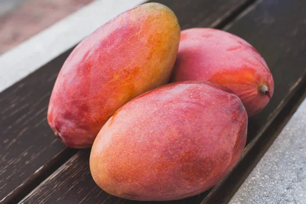 Sweet ripe mango fruits over wooden table — Stock Photo