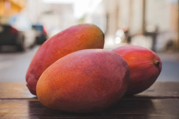 Sweet ripe mango fruits over wooden table — Stock Photo