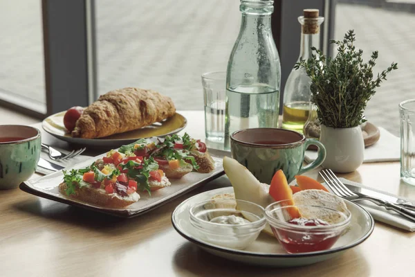 Vue rapprochée de délicieux petit déjeuner sain avec thé, gâteaux au fromage et sandwichs sur la table — Photo de stock