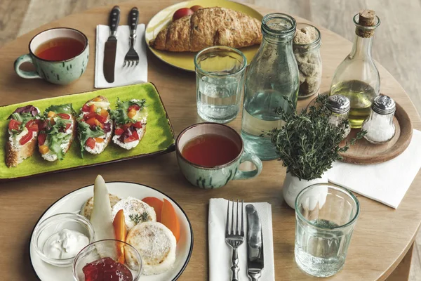 Delicioso desayuno saludable con té, tartas de queso y sándwiches en la mesa - foto de stock