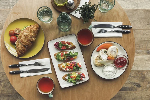 Верхний вид чашки, бутерброды и чизкейки на стол подается на завтрак — стоковое фото