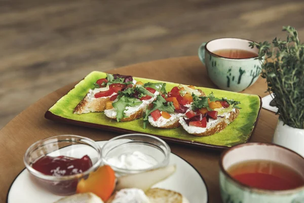 Vue rapprochée des sandwichs gastronomiques et du thé sur la table au petit déjeuner — Photo de stock