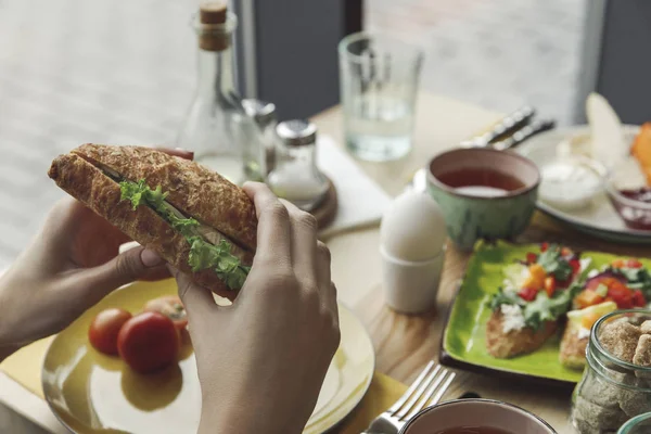 Cropped shot of person eating fresh tasty sandwich at breakfast — Stock Photo