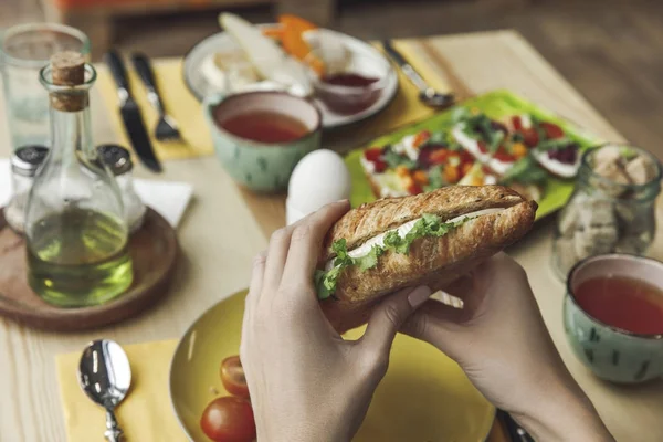 Частичный вид крупным планом человека, поедающего свежий вкусный сэндвич за завтраком — стоковое фото