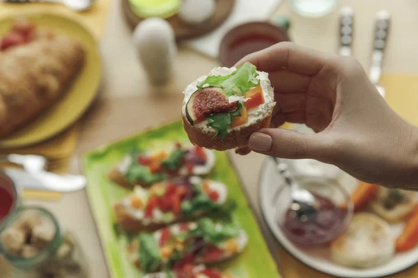 Close-up partial view of person holding delicious sandwich at breakfast — Stock Photo