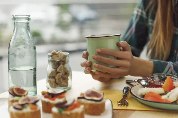 Cropped shot of girl holding cup of tea while having breakfast — Stock Photo