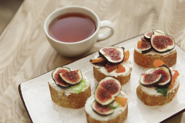 Primo piano vista di tartine con fichi e tazza di tè sul tavolo — Foto stock