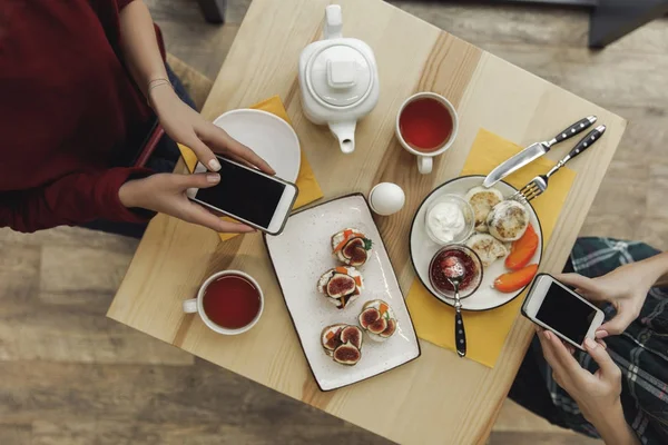 Vue de dessus des personnes utilisant des smartphones avec des écrans vides pendant le petit déjeuner — Photo de stock