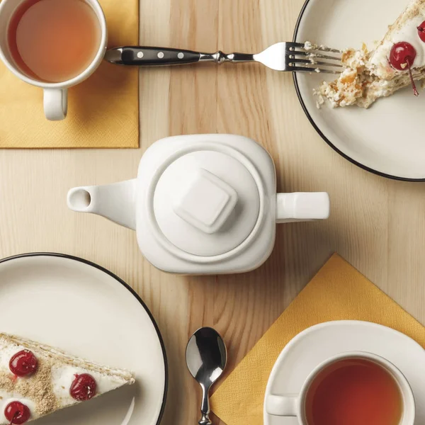 Close-up top view of kettle, two cups with hot tea and delicious pastries on table — Stock Photo