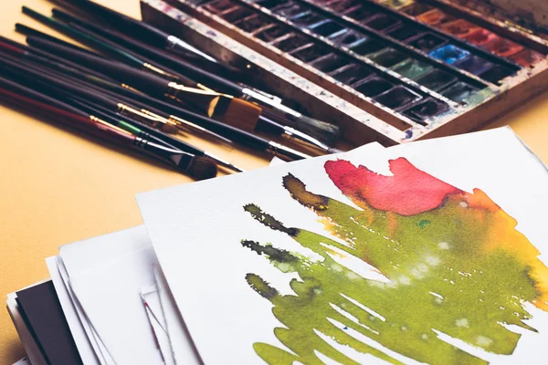 Vista ravvicinata di disegno astratto ad acquerello, vernici e pennelli sul posto di lavoro del progettista — Foto stock