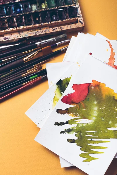 Vista superior de pinturas de acuarela, bocetos y pinceles en el lugar de trabajo del diseñador - foto de stock