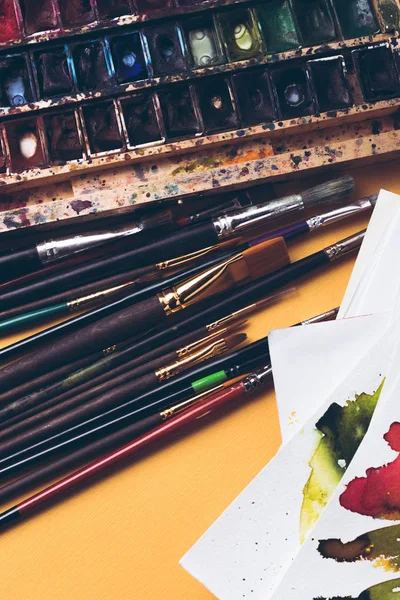 Close-up view of watercolor paints, sketches and paintbrushes at designer workplace — Stock Photo