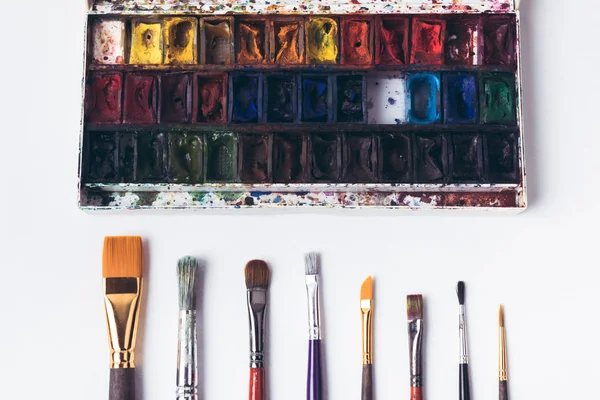 Top view of well organized paint brushes and watercolor paints on white — Stock Photo