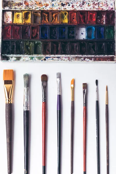 Vista dall'alto di pennelli e vernici ad acquerello ben ordinati sul posto di lavoro del progettista — Foto stock