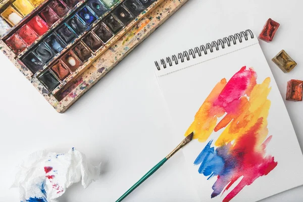 Draufsicht auf Aquarellfarben und Pinsel am Designerarbeitsplatz — Stockfoto