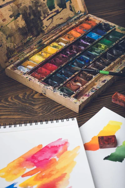 Close-up view of watercolor paints, paintbrush and abstract sketches at designer workplace — Stock Photo