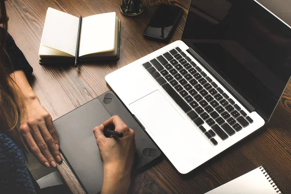 Vue partielle rapprochée du concepteur à l'aide d'un ordinateur portable et d'une tablette graphique sur le lieu de travail — Photo de stock