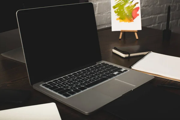 Close-up view of designer workplace with notebooks and laptop with blank screen — Stock Photo