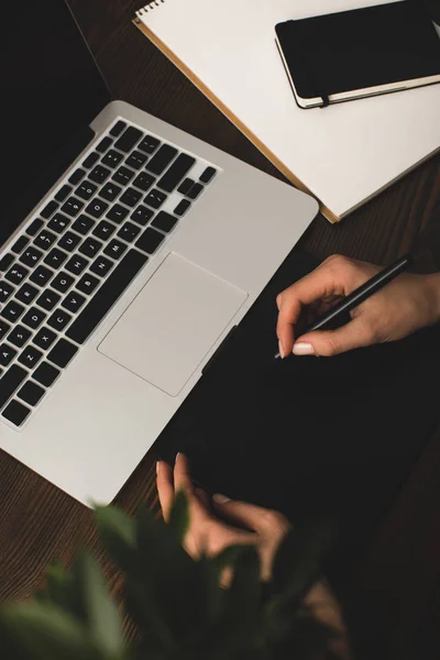 Enfoque selectivo de la persona que utiliza el ordenador portátil y tabletas gráficas en el lugar de trabajo - foto de stock