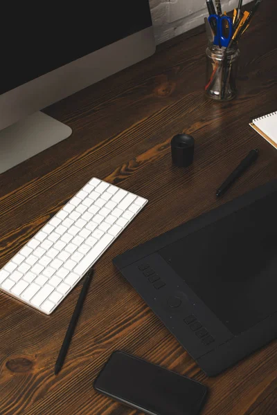 Vista de primer plano de la computadora de escritorio, tableta gráfica y teclado en la mesa de madera - foto de stock