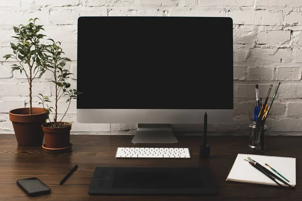 Ordenador de sobremesa con pantalla en blanco, tableta gráfica y smartphone sobre mesa de madera - foto de stock