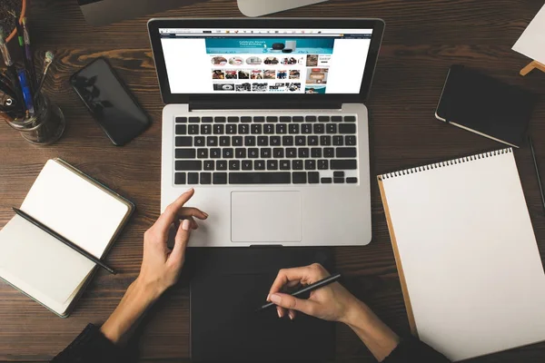 Cropped shot of designer using graphics tablet and laptop with amazon website on screen — Stock Photo