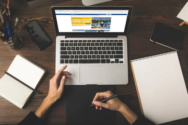 Cropped shot of designer using graphics tablet and laptop with booking website on screen — Stock Photo