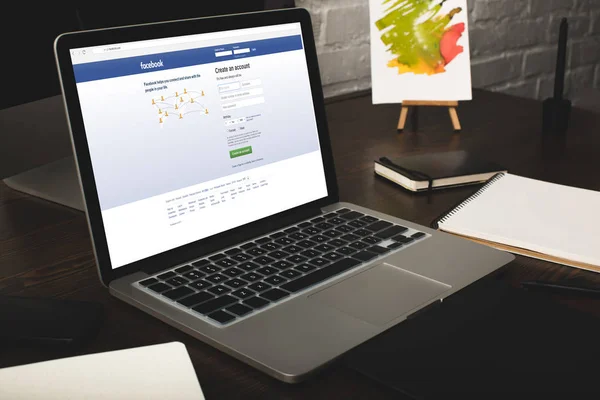 Designer-Arbeitsplatz mit Laptop und Facebook-Website auf dem Bildschirm — Stockfoto