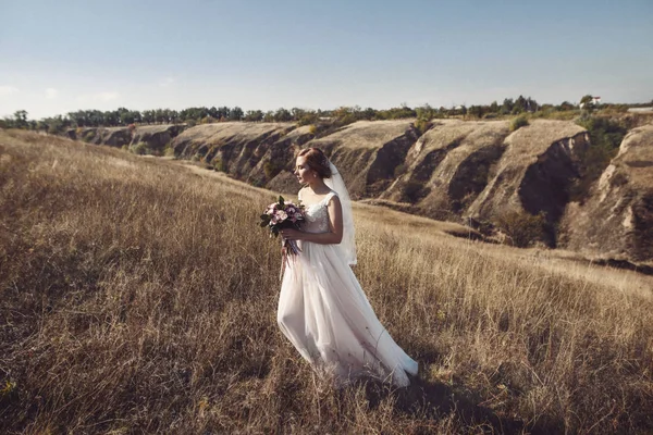 Schönheit Braut in Brautkleid mit Strauß und Spitzenschleier auf die Natur. schöne Modell Mädchen in einem weißen Hochzeitskleid. Frauenporträt im Park. Frau mit Frisur. Nette Dame im Freien — Stockfoto