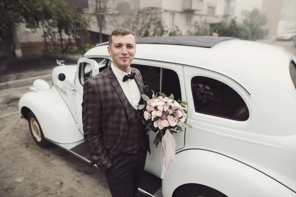 Ευτυχισμένος πολυτελή γάμος γαμπρός κοντά αυτοκίνητο ρετρό στην ομίχλη του φθινοπώρου — Φωτογραφία Αρχείου