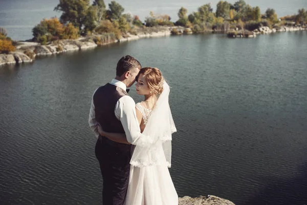 結婚式の日に湖の近く歩く美しい若いカップル — ストック写真