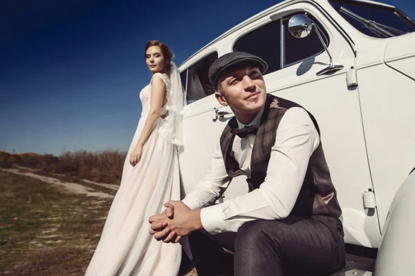 Szép menyasszony és a vőlegény jóképű a retro autó — Stock Fotó