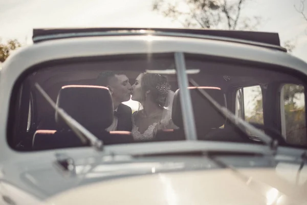 De bruid en bruidegom plezier achter het stuur van retro auto. Bruiloft. — Stockfoto