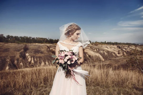 Schönheit Braut in Brautkleid mit Strauß und Spitzenschleier auf die Natur. schöne Modell Mädchen in einem weißen Hochzeitskleid. Frauenporträt im Park. Frau mit Frisur. Nette Dame im Freien — Stockfoto