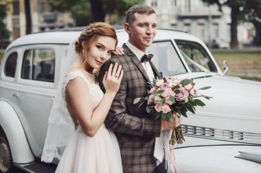 Mutlu gelin ve damat sarılma ve düğün töreni önce eski retro otomobil Sedan yakınındaki poz