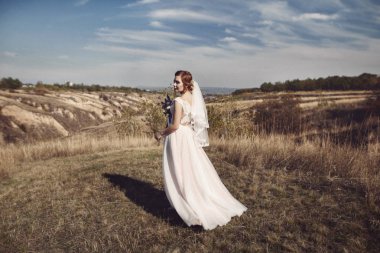 Güzellik gelin buketi ve dantel örtü niteliğine ile gelinlik elbisesi içinde. Güzel model kız beyaz bir gelinlik. Kadın portre parkta. Saç modeli olan kadın. Sevimli Bayan açık havada