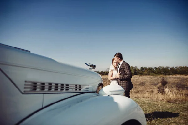Een prachtige zoek bruid en bruidegom naast een vintage bruiloft auto — Stockfoto