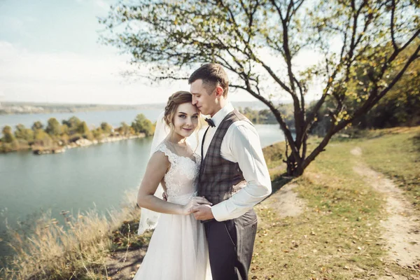 Prachtig bruidspaar zoenen en omhelzen bij de oever van een bergrivier met stenen — Stockfoto