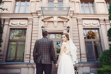 Gelin ve damat ile el ele tutuşarak ve kameraya bakıyor