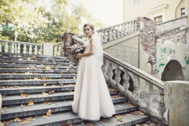 Gelin buketi ayakta merdivenlerde ile gülümseyen.