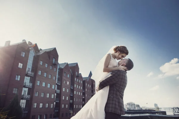 Recém-casados se beijando na frente do prédio — Fotografia de Stock