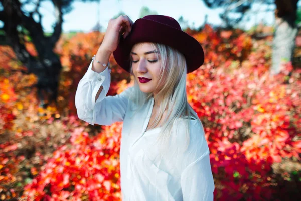 Fashion Woman in Hat on red Autumn Background in Sunny Day (dalam bahasa Inggris). Potret Perempuan . — Stok Foto