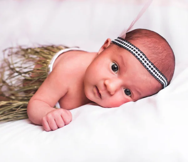 Doce menina deitada em um backdropHeadband branco com pena — Fotografia de Stock