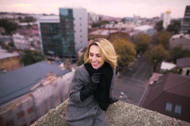 Cityscape ile bir gökdelenin tepesinde oturan gülümseyen mutlu 