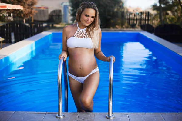 Hermosa mujer embarazada subiendo de la piscina, pasar las vacaciones de verano en un resort de lujo, concepto de embarazo feliz —  Fotos de Stock