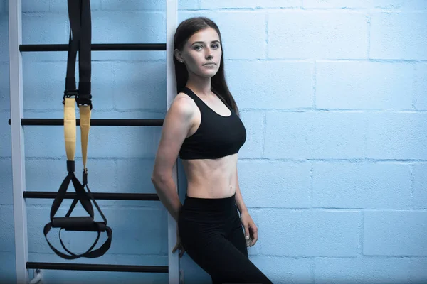 Mladá atraktivní žena trénink s htrx fitness popruhy v tělocvičně na studiu — Stock fotografie